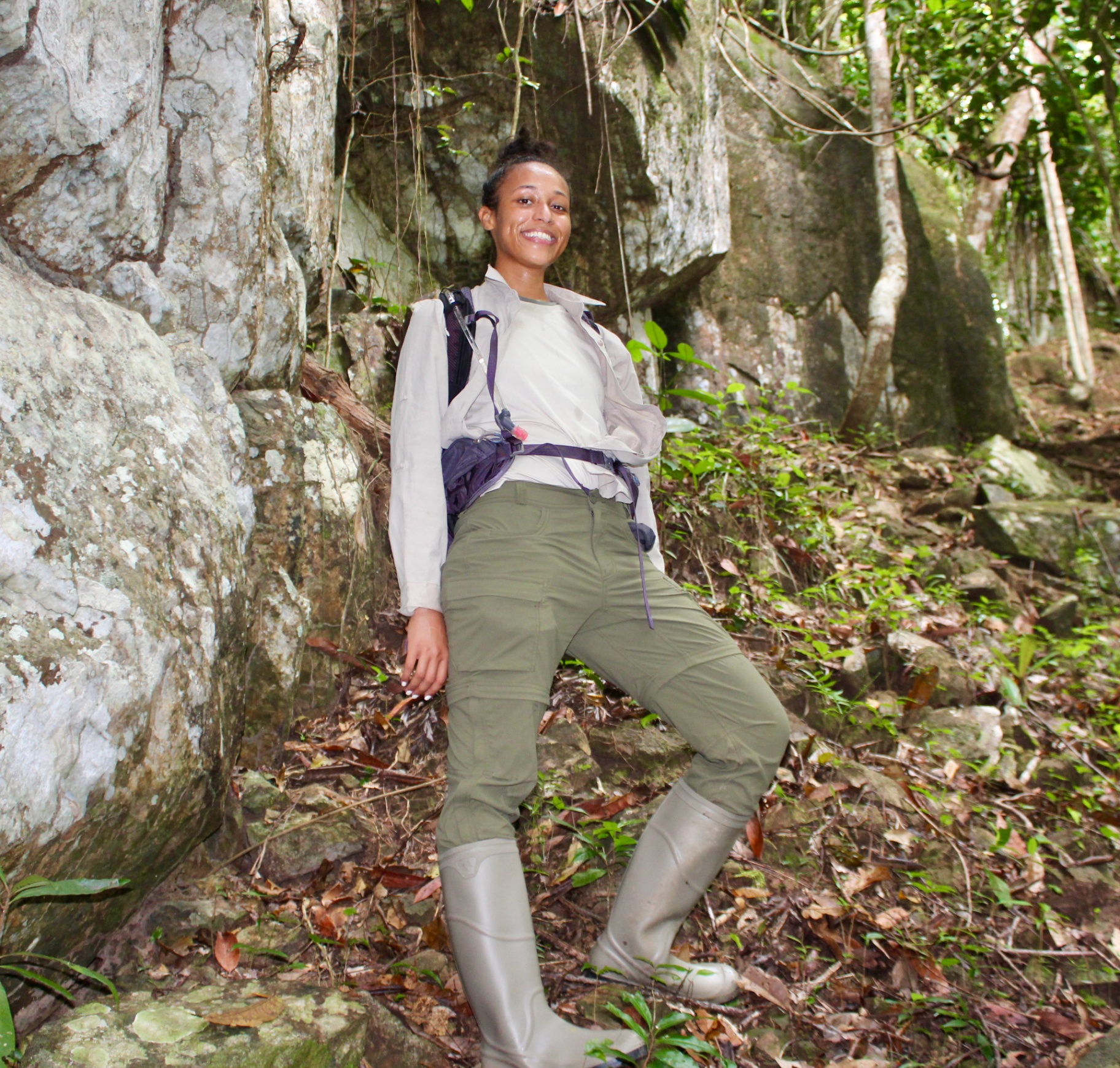 Cynthia leaning against a moss-streaked boulder in the Guyanese forest